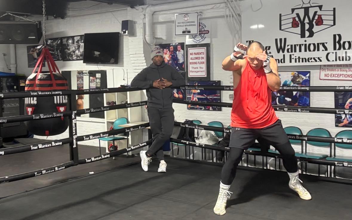 Zhilei Zhang shadowboxes as trainer Shaun George looks on.