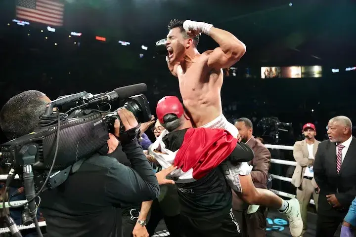 Jose Armando Resendiz is raised in the air by a team member, with Resendiz's wrapped hands up in the air and his biceps muscles flexed as he celebrates his victory over Caleb Plant on May 31, 2025.