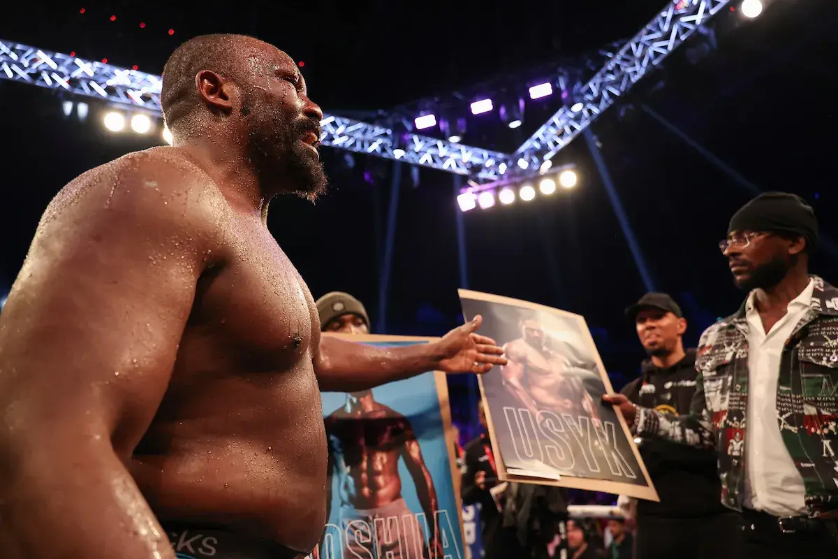 Derek Chisora points to a poster of Oleksandr Usyk after defeating Otto Wallin.