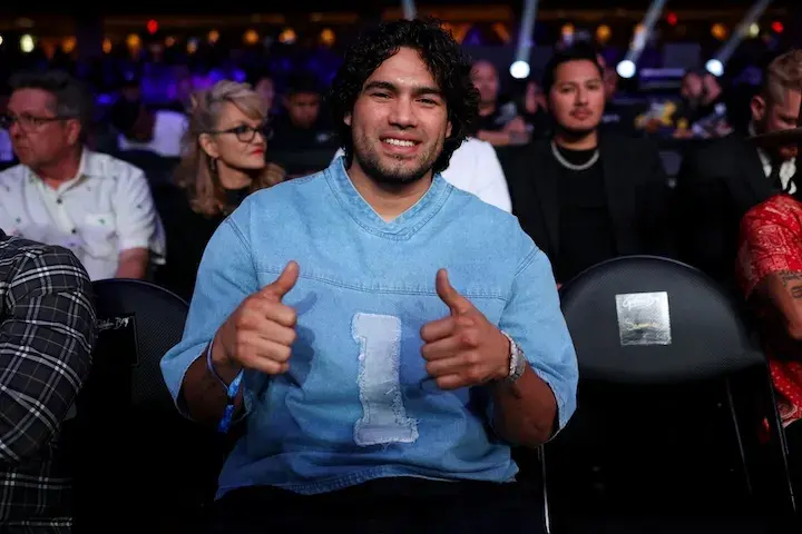 Gilberto "Zurdo" Ramirez is shown wearing a blue shirt with the number 1 in white on his chest. He is seated in an arena holding two thumbs up and smiling.