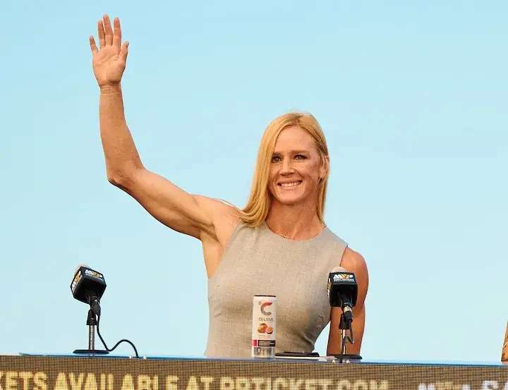 International Boxing Hall of Fame inductee Holly Holm waves at a December 2025 press conference, days ahead of her first boxing match in years.