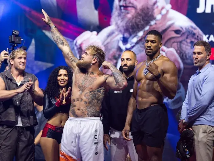 Jake Paul and Anthony Joshua stand onstage after weighing in on December 18, 2025.