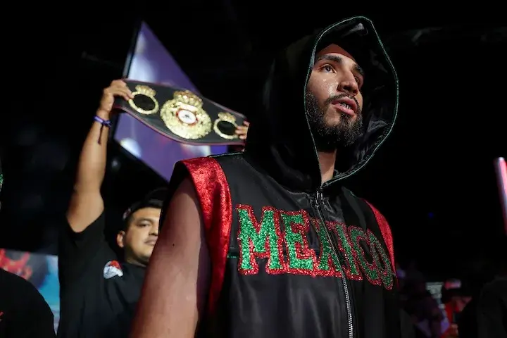 Joel Iriarte walks to the ring, with a team member behind him holding a title belt in the air, for his fight with Eduardo Hernandez Trejo on September 20, 2025.