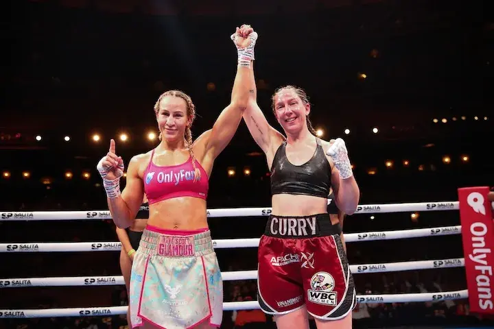 Olivia Curry and Kaye Scott hold each other's hands in the air after fighting to a draw in their WBA and WBC middleweight title fight on September 19, 2025.