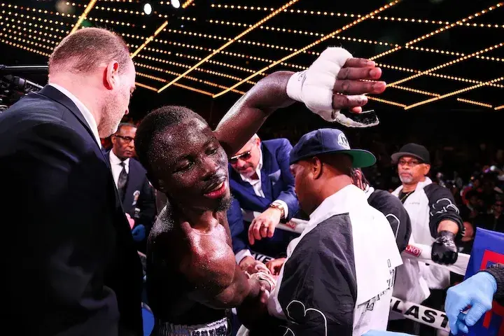 Richardson Hitchins stands in the ring surrounded by people and reaches toward someone with his left hand following his victory over George Kambosos on June 14, 2025.
