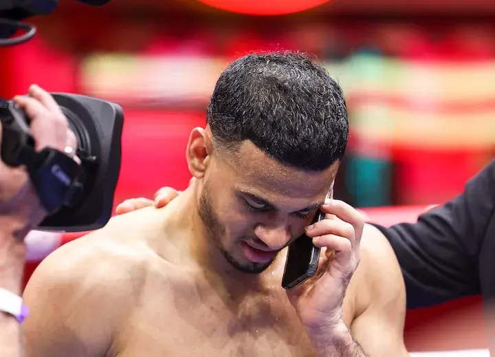 Rolando "Rolly" Romero holds a cellphone to his left ear while standing shirtless in a boxing ring at a workout ahead of his May 2025 fight in Times Square.