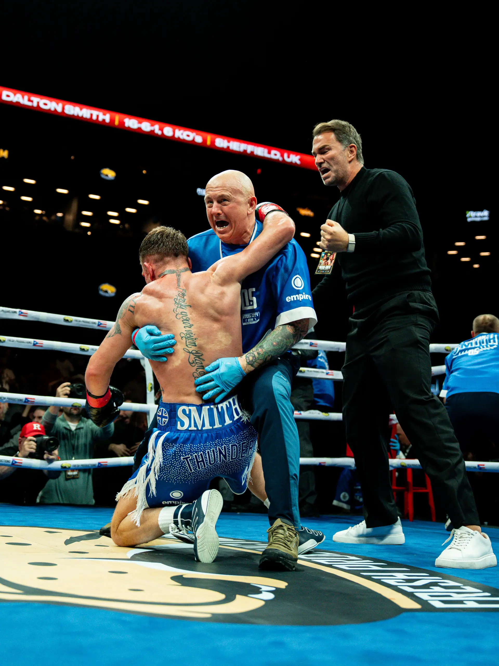 Dalton Smith drops to the canvas in celebration after stopping Subriel Matias to win the WBC junior welterweight world title on January 10, 2026. Promoter Eddie Hearn, clad in black, enters the ring to celebrate with him.