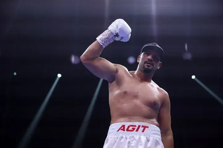 Agit Kabayel raises his right glove in the air while standing in an arena.