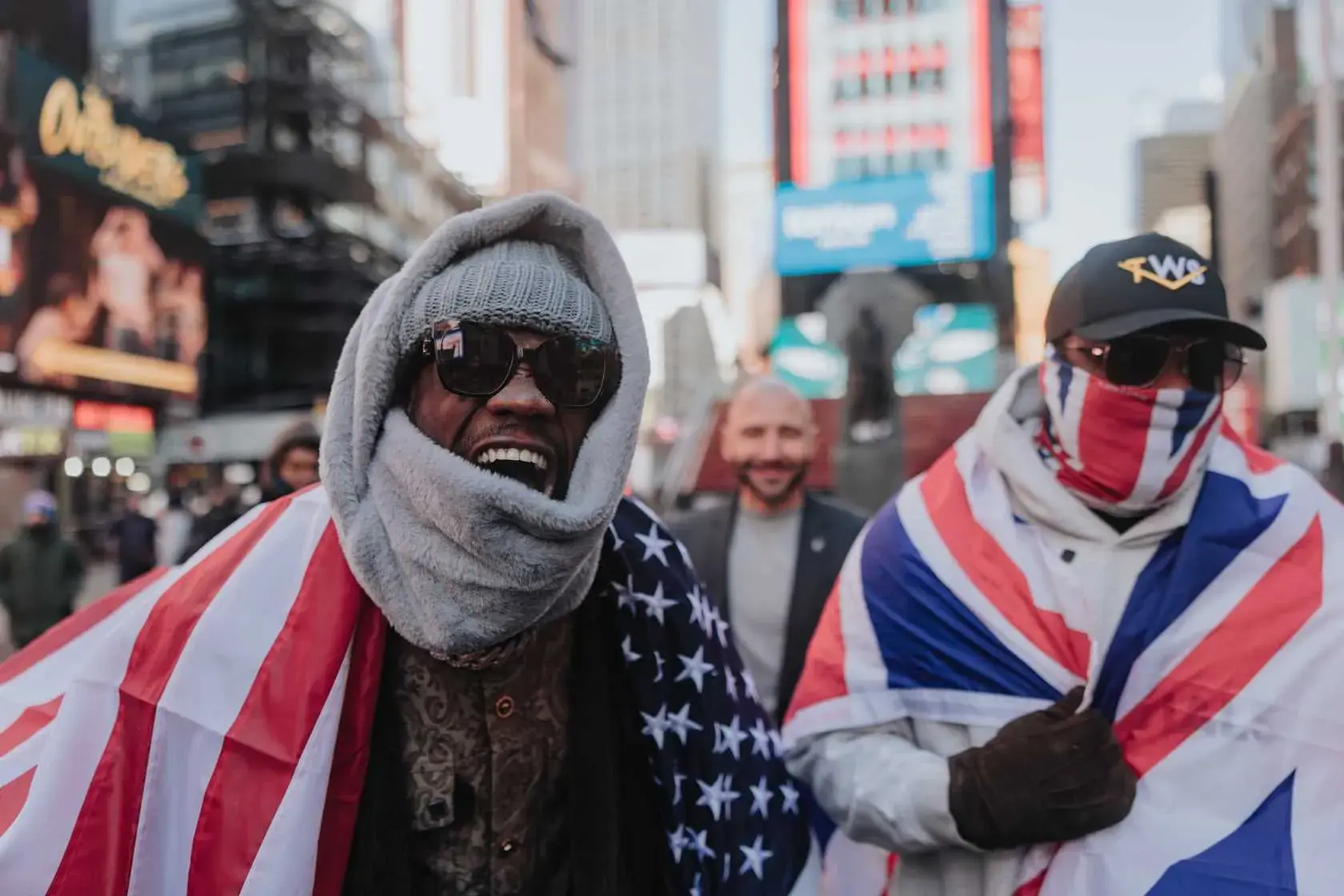 Deontay Wilder and Derek Chisora wrap themselves in their respective countries' flags at a media event in New York City ahead of their April 4, 2026, bout in London.