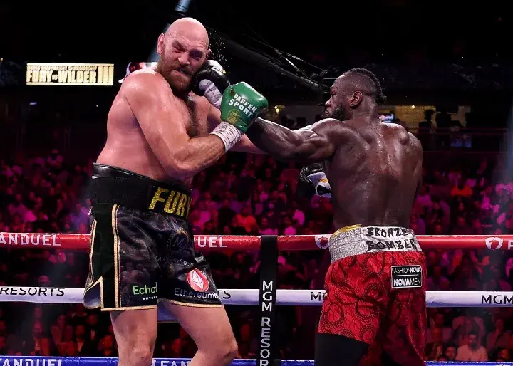 Tyson Fury swallows a left hand from Deontay Wilder during their 2021 third battle