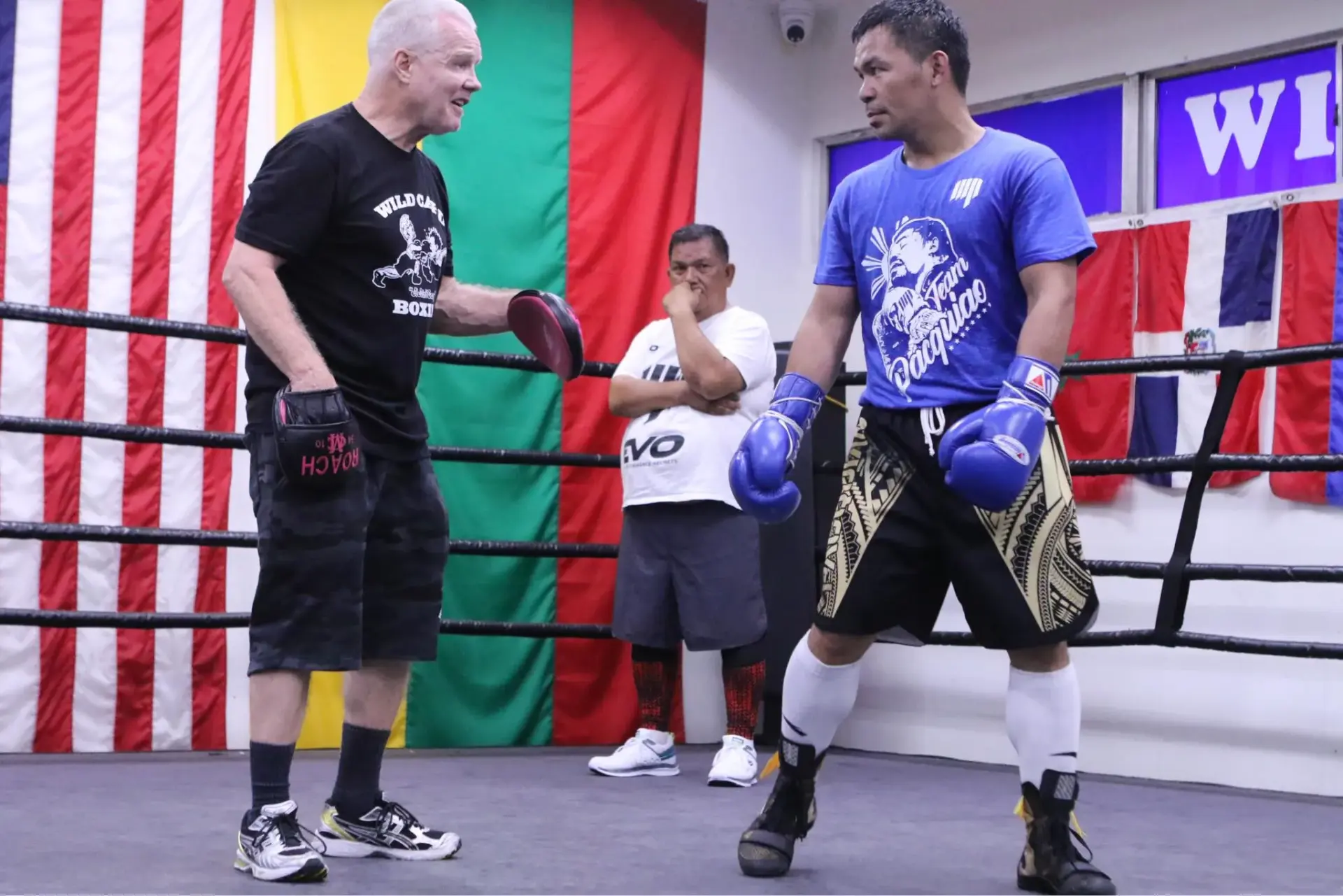 Manny Pacquiao hits the pads with Freddie Roach as Buboy Fernandez watches on